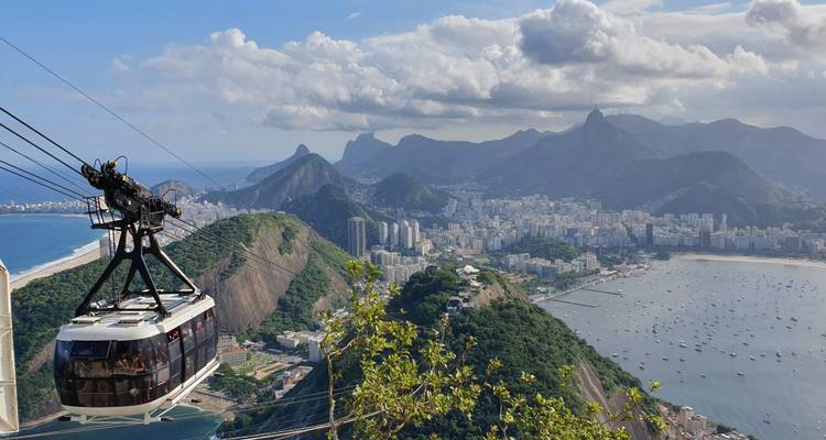 Teleférico subiendo la montaña Pan de Azúcar con vista panorámica de la costa de Río de Janeiro y su horizonte urbano.