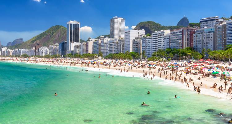 Multitudes disfrutando del surf turquesa y las arenas blancas de la Playa de Copacabana respaldadas por hoteles de gran altura.