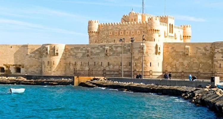 Forteresse côtière en pierre avec des tours crénelées donnant sur les eaux turquoise de la Méditerranée sous un ciel dégagé.