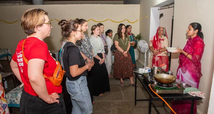 Cours de cuisine où les voyageurs regardent un instructeur préparer un plat indien traditionnel à l'intérieur.