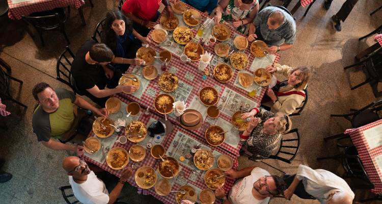 Vue de dessus d'une longue table où les voyageurs savourent ensemble un repas indien copieux.