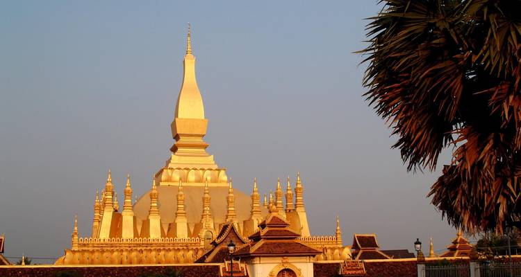 Die goldene Pha That Luang Stupa erstrahlt im warmen Abendlicht vor einem klaren Himmel.