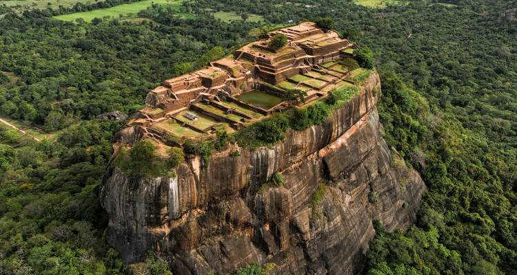 Luchtfoto van de Sigiriya rotsfort die uit het dichte bos omhoog rijst.