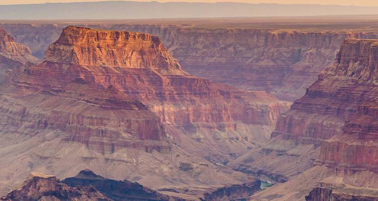 Soft sunrise light bathes layered cliffs deep within the Grand Canyon.