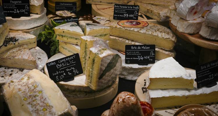 Comptoir de fromages artisanaux garni de portions crémeuses et de panneaux de prix sur tableau noir.