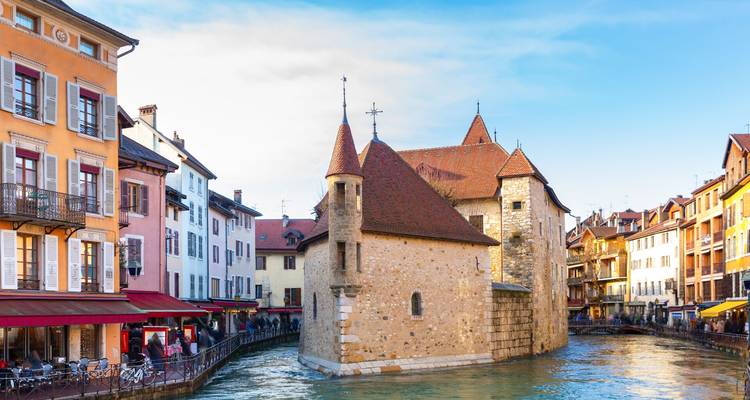 Le Palais de l'Isle historique se dresse au milieu du canal turquoise d'Annecy, encadré par des maisons aux couleurs pastel.