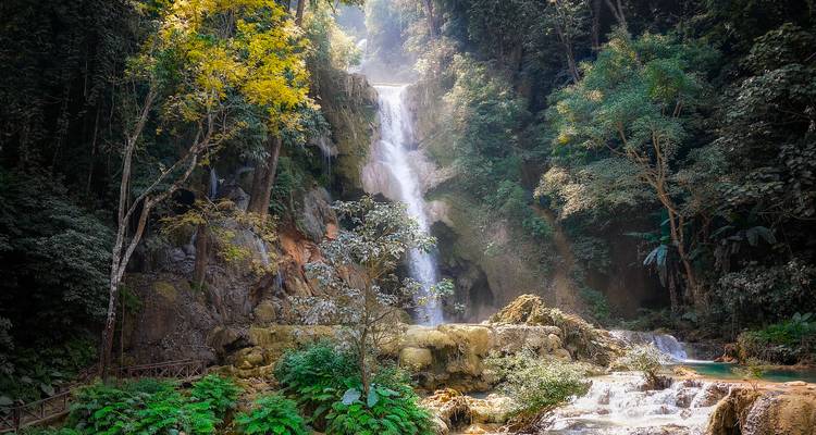 Lush jungle setting with the multi-tier Kuang Si Waterfall cascading into turquoise pools.
