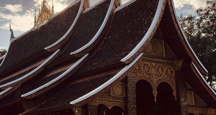 Serpentine multi-tier roof of a temple silhouetted against a dusky sky.