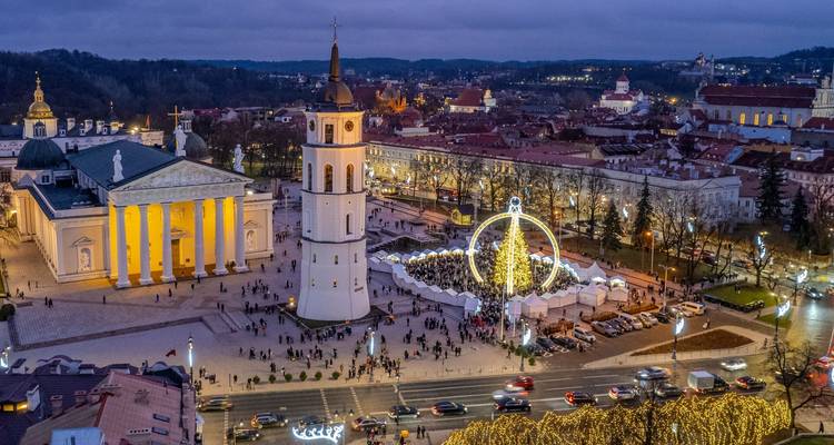 Vue aérienne au crépuscule de la place de la cathédrale de Vilnius avec le clocher blanc, les colonnes illuminées et le marché de Noël.