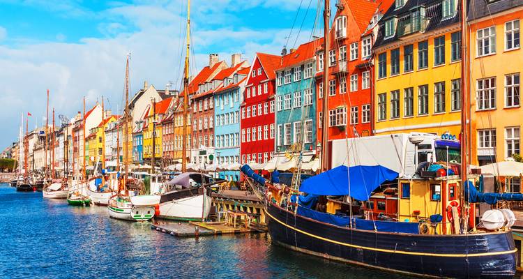 Vibrante fila de casas multicolores y barcos amarrados a lo largo del icónico canal Nyhavn de Copenhague en un día soleado.