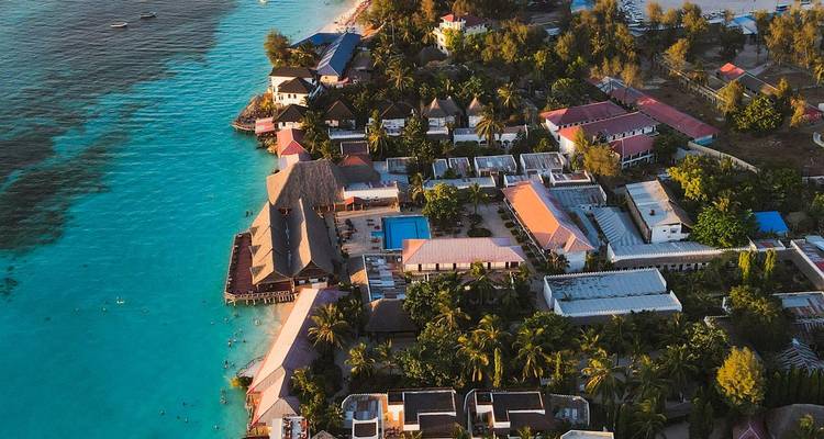 Luftaufnahme eines Küstenresorts, das sich entlang von leuchtend türkisfarbenen Gewässern erstreckt.