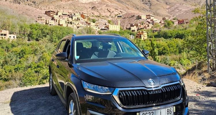 SUV noir garé sur un point de vue dominant un petit village de montagne marocain.