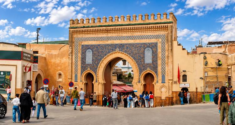 Las multitudes pasan a través de la ornamentada puerta Bab Boujloud con azulejos azules en la entrada de la medina de Fes.