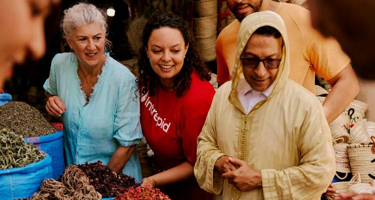 Les voyageurs examinent des tas d'herbes séchées et d'épices à un étal de marché marocain traditionnel.
