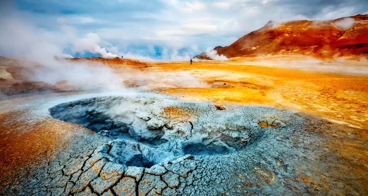 Champ géothermal coloré avec des évents fumants et une croûte minérale fissurée.