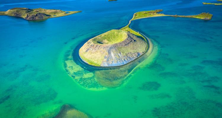 Lac d'un magnifique vert-bleu entourant un petit cratère d'île volcanique vu de haut.