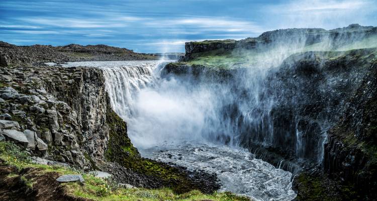 La cascade de Dettifoss se précipite à travers une gorge rocheuse en projetant des embruns vers le ciel.