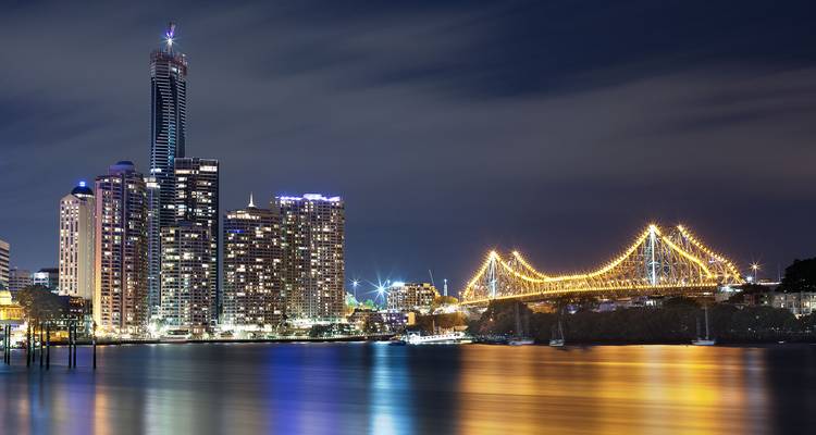 Skyline nocturne de Brisbane avec les reflets scintillants du fleuve et le Pont Story illuminé.