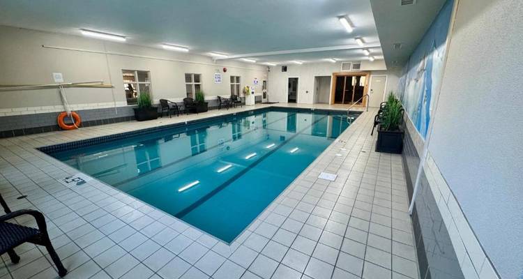 Rechteckiger Indoor-Hotelswimmingpool mit Fliesenbelag und Sitzbereichen.