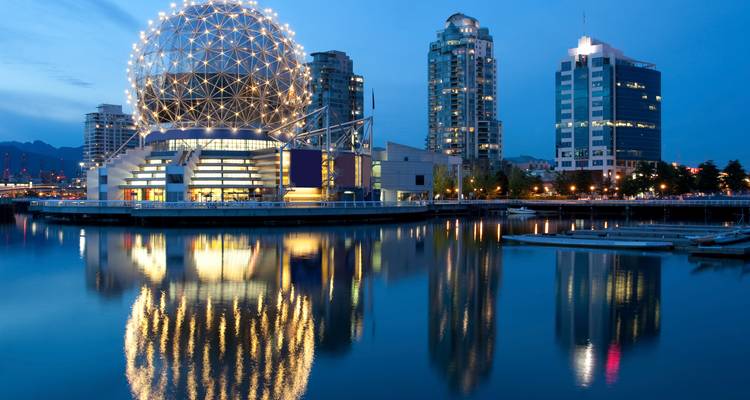 Die beleuchtete geodätische Kuppel des Science World spiegelt sich in den ruhigen Gewässern des Abends in der Innenstadt von Vancouver.