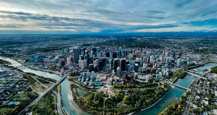 Luftaufnahme des Zentrums von Calgary, das vom Bow River umgeben ist, unter dramatischem Himmel.
