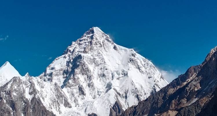 Vue nette d'un pic montagneux imposant recouvert de glace sur un ciel bleu profond.