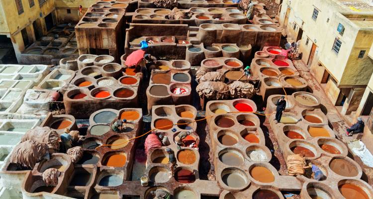 Coloridas tinas de tinte en la vista de la azotea de las curtidurías de cuero de Fes ocupadas con trabajadores.