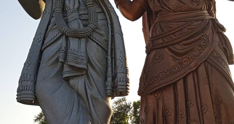 Onderaanzicht van verfraaide Hindu-standbeelden gekleed in gebeeldhouwde gewaden, gegegen tegen het zonlicht.