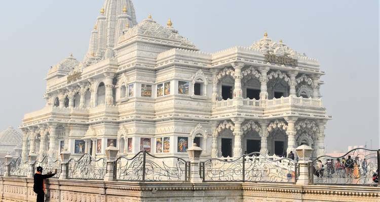 Bezoeker fotografeert de ingewikkeld uitgehouwen witte marmeren Prem Mandir-tempel.