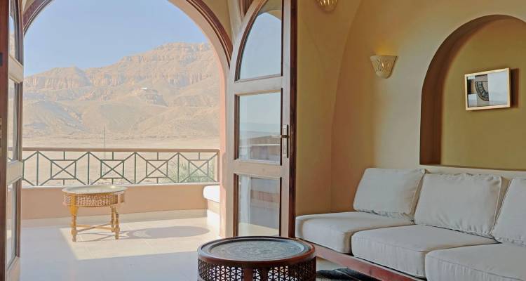Inviting lounge room with cream sofa opening to balcony view of Theban mountains in Luxor