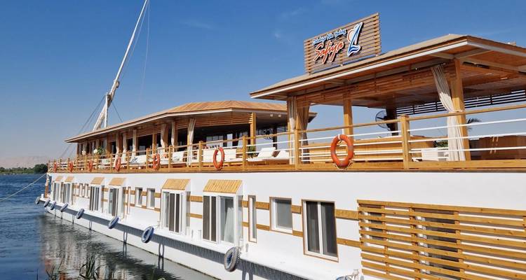 Traditional wooden Nile cruise vessel moored on calm water under blue sky