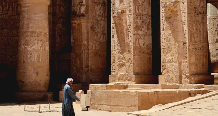 Local man walking past massive carved columns of an ancient Egyptian temple