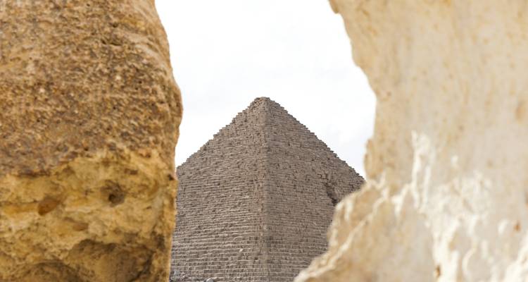Stone pyramid peak seen through natural rock framing creating dramatic perspective