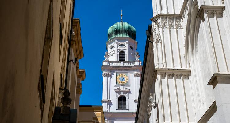 Clocher baroque blanc avec dôme vert émergeant entre les murs des ruelles étroites à Passau