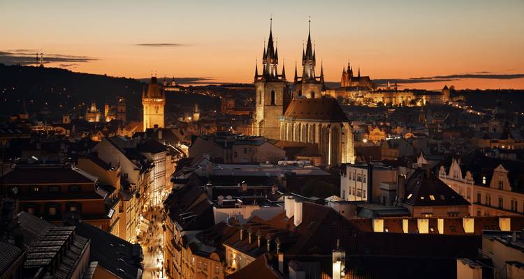 Coucher de soleil magique sur la Vieille Ville de Prague avec les flèches illuminées de l'Église Týn et le Château de Prague baignés dans une lumière chaleureuse.