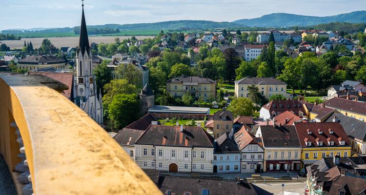 Toits de la ville et paysage rural aperçus par-dessus un parapet jaune avec des collines lointaines à l'horizon