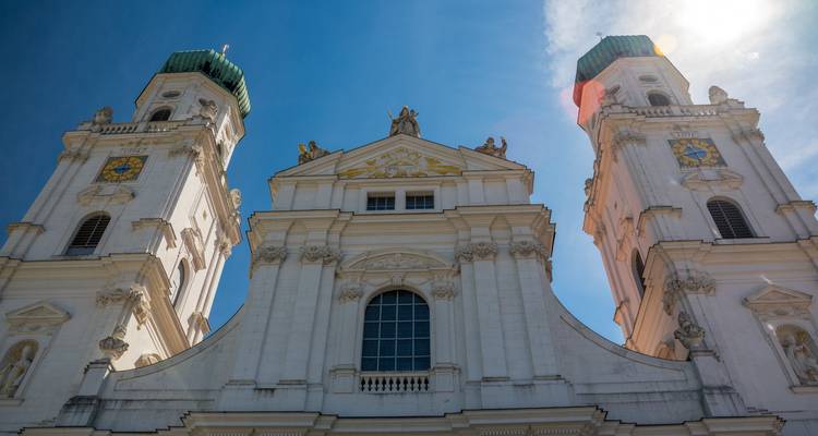 Opwaarts zicht op witte barokke kathedraal torens van Passau tegen een helderblauwe lucht.