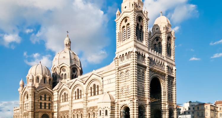 Catedral de piedra a rayas con cúpulas y torres gemelas recortada contra un cielo azul brillante