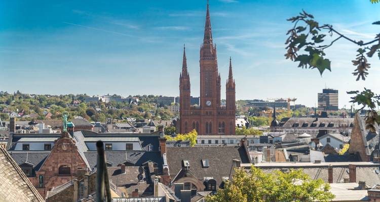 Vue lointaine de l'horizon de Wiesbaden avec des flèches d'église rouges élancées encadrées par le feuillage
