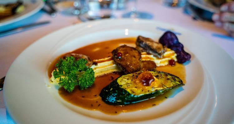 Plat gastronomique présenté avec des légumes, une sauce et une garniture de brocoli en restaurant.