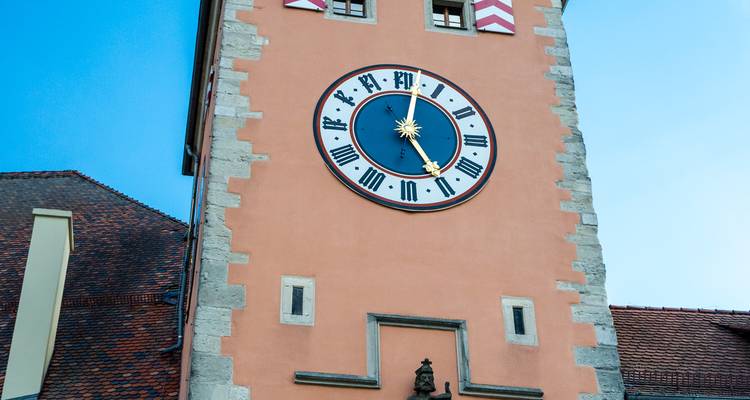 Gros plan d'une grande horloge décorative sur une tour de couleur pêche à Ratisbonne.