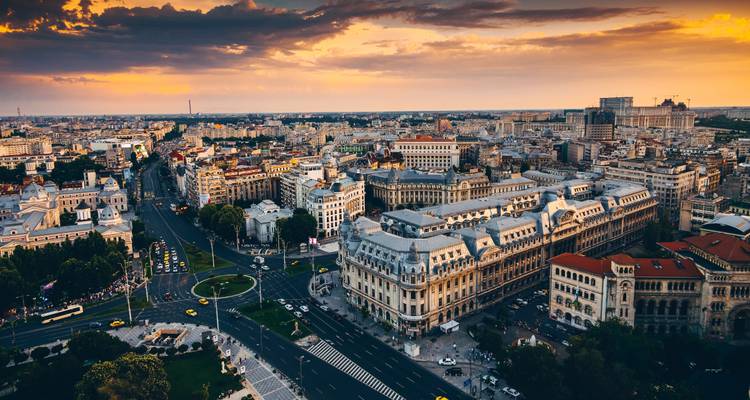 Vue aérienne panoramique du coucher de soleil sur le centre-ville de Bucarest avec ses grands boulevards, ses bâtiments historiques et ses ciels luminescents.