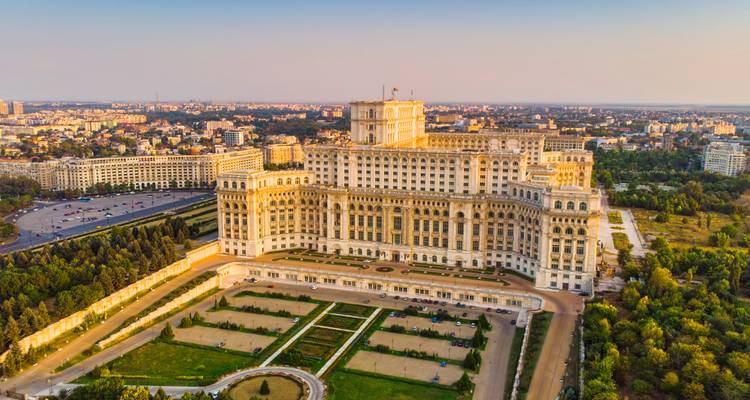 Le complexe massif du Palais du Parlement dominant la skyline de Bucarest à la lumière douce du soir.
