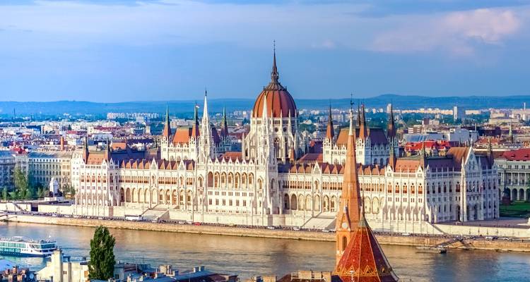 El icónico Edificio del Parlamento Húngaro extendiéndose a lo largo del Río Danubio bajo una brillante luz diurna
