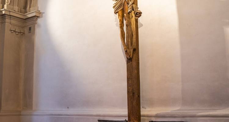 Grand crucifix en bois exposé dans l'intérieur faiblement éclairé d'une église historique.