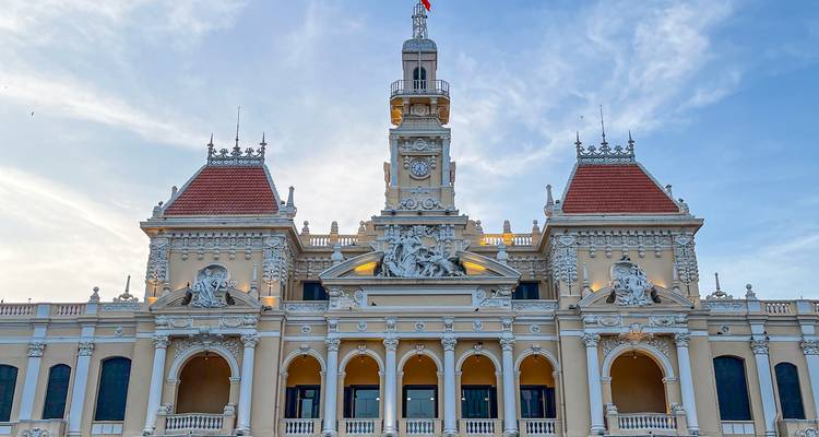 L'architecture coloniale française ornementée de l'Hôtel de Ville de Ho Chi Minh-Ville illuminée par la lumière dorée du soir contre un ciel pastel.