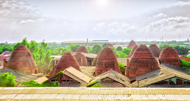 Panorama ensoleillé des fours à briques traditionnels parsemant le paysage du village de poterie de Vinh Long.