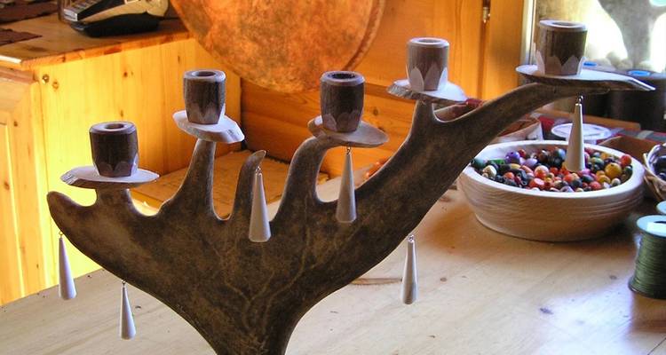 Hand-crafted antler candelabra displayed on a wooden table inside a rustic workshop.