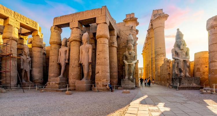 Kolossale Statuen und aufragende Säulen säumen den großen Hof des Luxor-Tempels, der in warmem Licht erstrahlt.