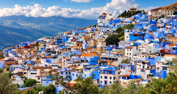 Vista panorámica de la medina azul de Chefchaouen desde la ladera bajo nubes dramáticas.
